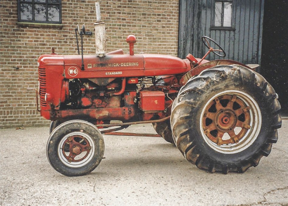 Rød McCormick-traktor, kalt «Derringen», parkert foran en murvegg på Grefsheim.