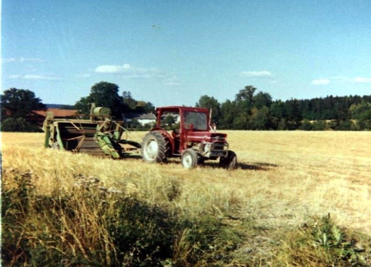 Rød traktor som trekker en grønn slepetresker over en stubbåker.